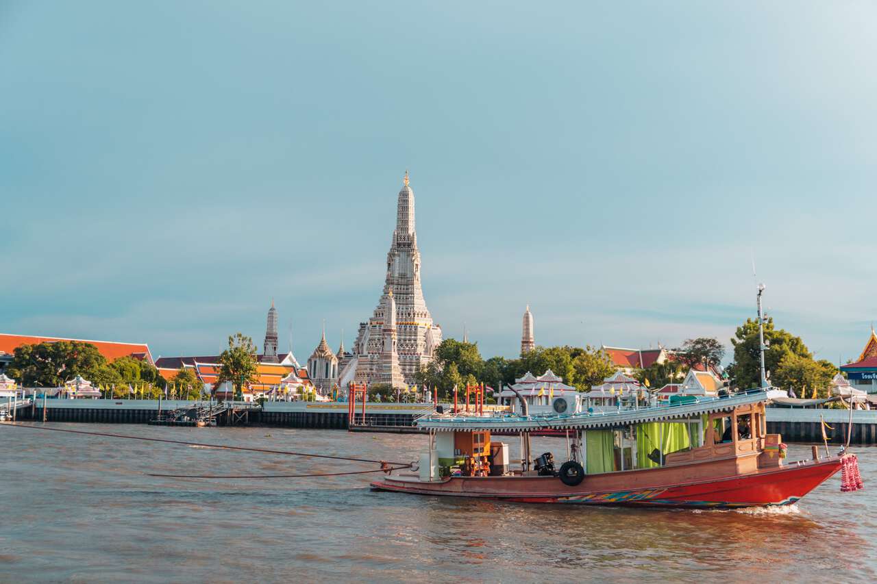 Một chiếc thuyền đi qua Wat Arun ở Bangkokg