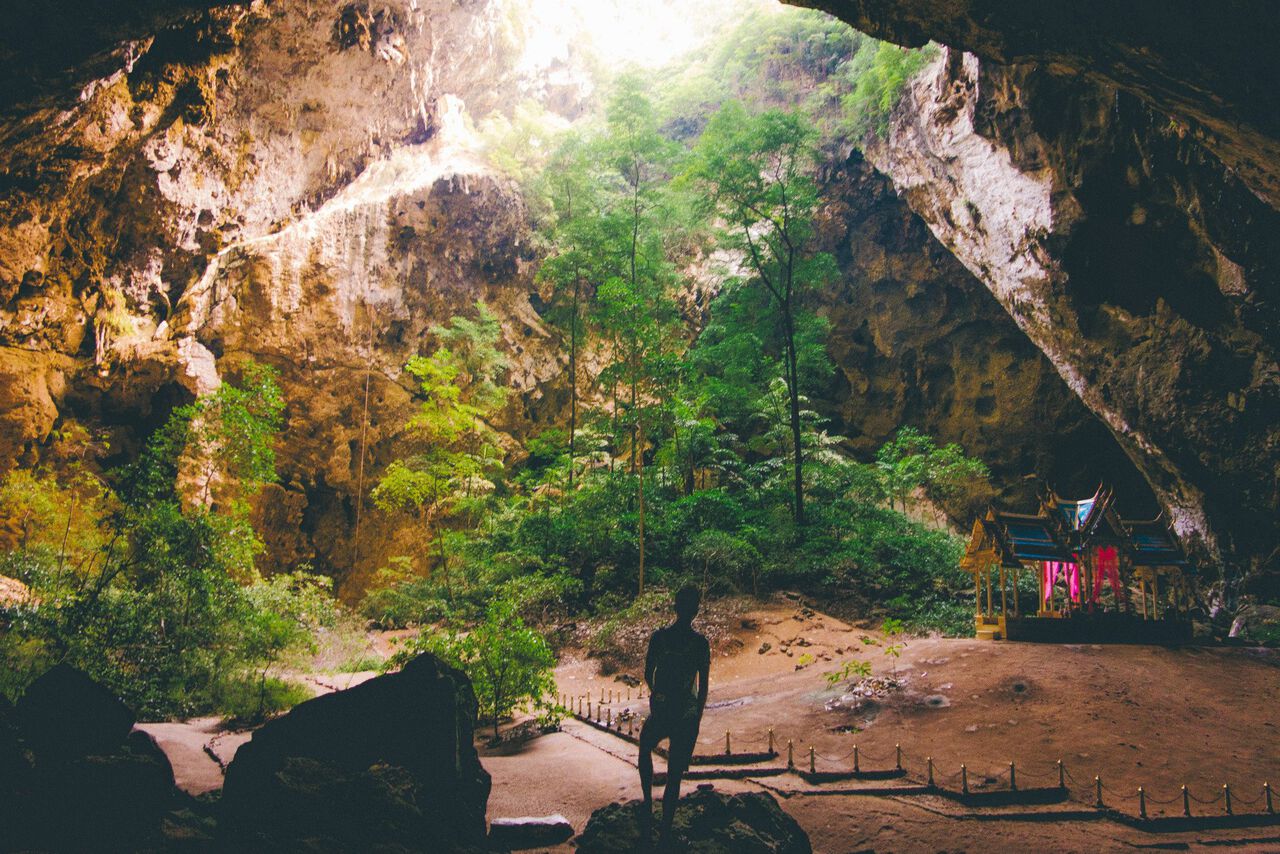 Một người đang ngắm nhìn ngai vàng và cây cối mọc um tùm bên trong hang động Phraya Nakhon ở Hua Hin, Thái Lan