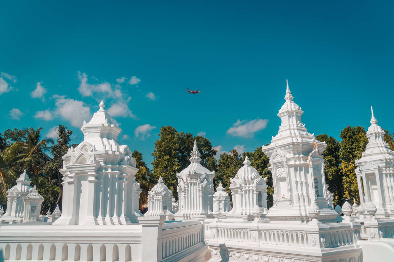 Một chiếc máy bay bay phía trên những ngôi chùa trắng Wat Suan Dok ở Chiang Mai, Thái Lan.